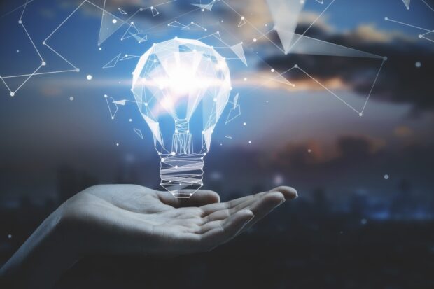 A hand holding a digital concept of innovation with a futuristic light bulb design