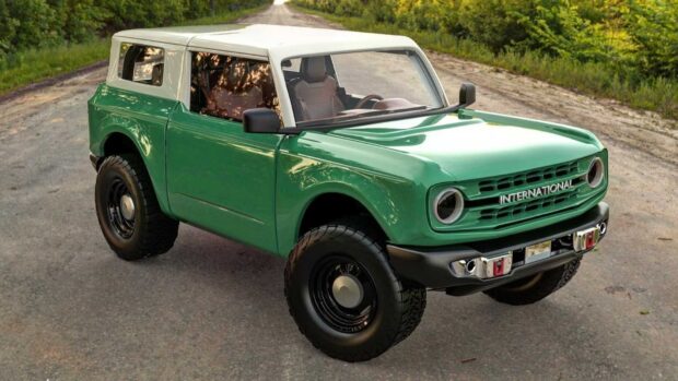 Green International Harvester vehicle parked on a rural road with trees in the background