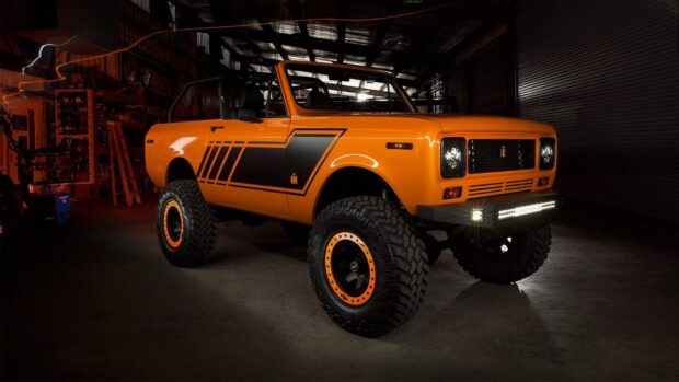 Orange International Harvester vehicle with offroad tires in a dark garage