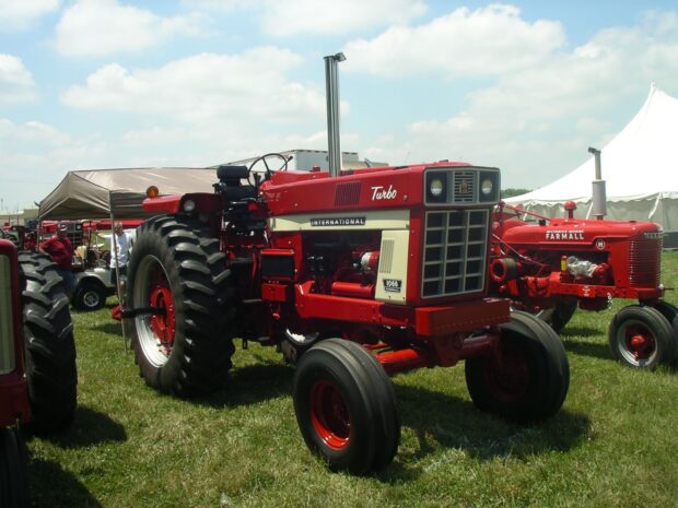 Red International Harvester tractor displayed at an outdoor event with blue sky and green grass