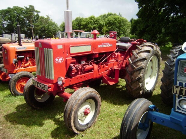 Red International Harvester tractor parked on grass with other tractors in the background