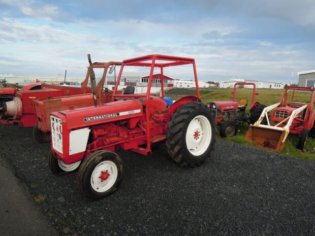 Red International Harvester tractor parked on gravel with other farming equipment