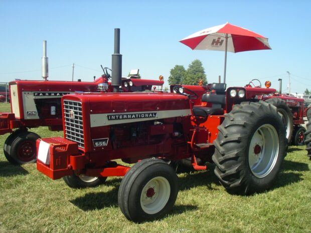 Red International tractor model 656 parked on grass under clear blue sky
