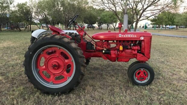 Vintage International Harvester Farmall tractor parked on grassy field in daylight