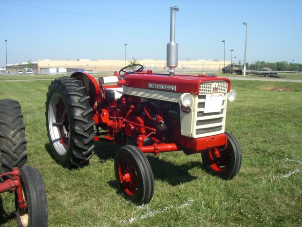 Vintage International Harvester tractor parked on green grass under clear blue sky