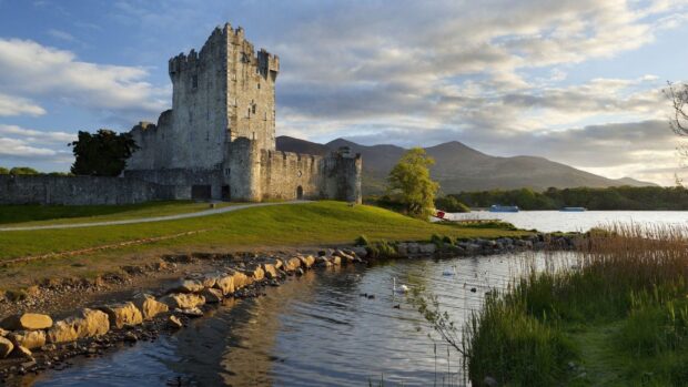 Historic Irish Countryside castle near a serene lake with mountains in the background