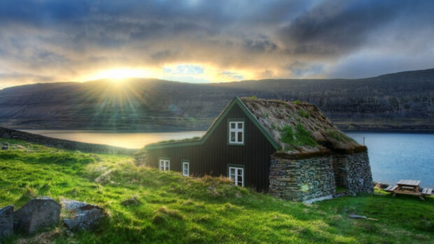 Traditional Irish countryside cottage with grass roof near lake at sunrise