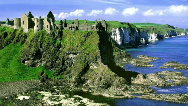 Ancient Irish countryside castle ruins on rocky cliffs near the ocean