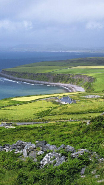 Lush green Irish countryside with rocky hills and a coastal bay view
