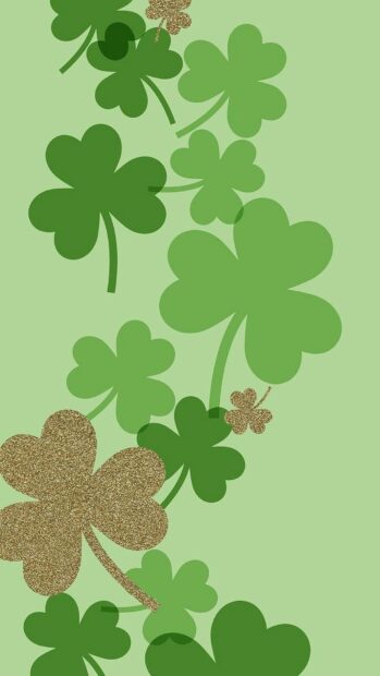 Various green and gold glitter Irish shamrock leaves on a light green background