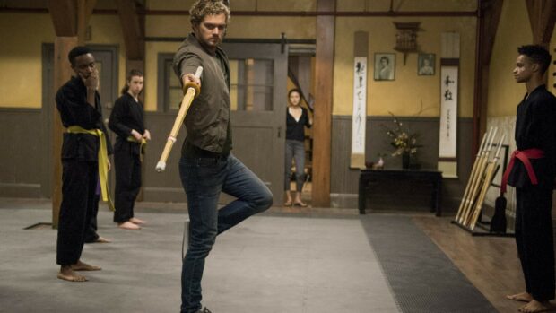 A man practices martial arts with a staff in a dojo training session