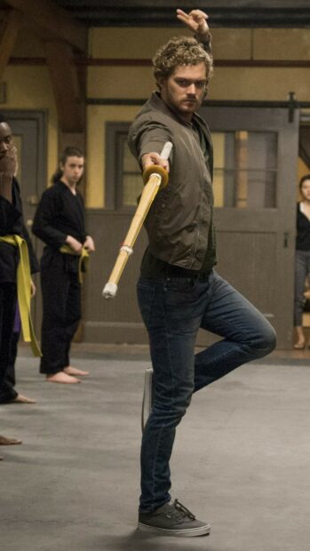 A man demonstrating martial arts moves with a staff in an Iron Fist training session