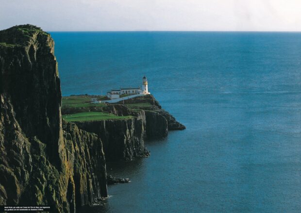 A lighthouse stands on rugged cliffs overlooking the sea in Isle of Skye