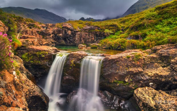A scenic view of Isle of Skye landscape with flowing waterfalls and rocky terrain
