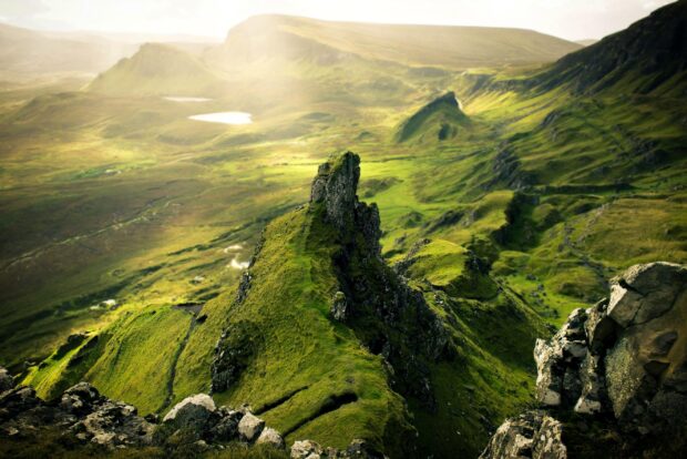 A rugged green landscape of cliffs and hills on Isle of Skye under soft sunlight