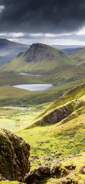 Green hills and rugged cliffs on the Isle of Skye under a cloudy sky