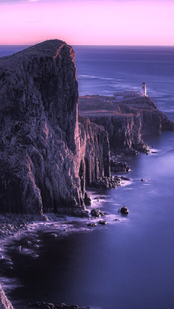 Dramatic Isle of Skye cliffside illuminated by sunset light near a lighthouse
