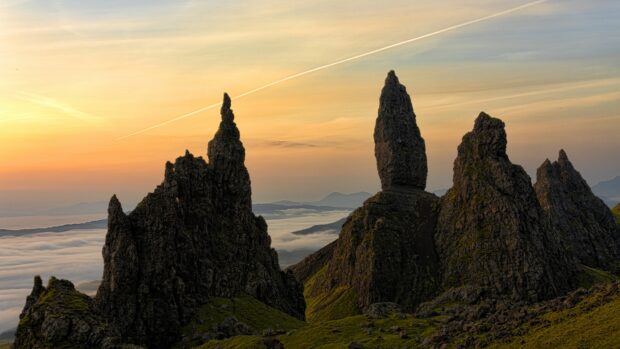 Jagged rock formations of Isle Of Skye seen during sunrise with mist and mountains in the background