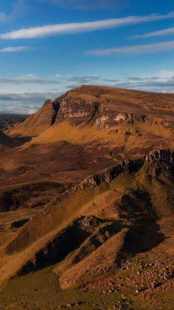 Rugged hills and cliffs on Isle of Skye landscape under blue sky