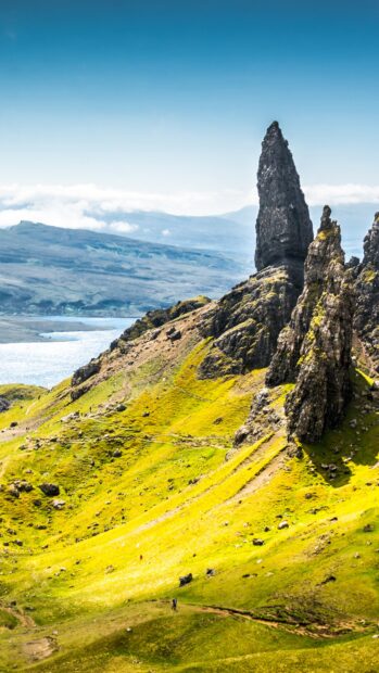 The Isle Of Skye rock formation stands tall on the green hillside under a clear blue sky