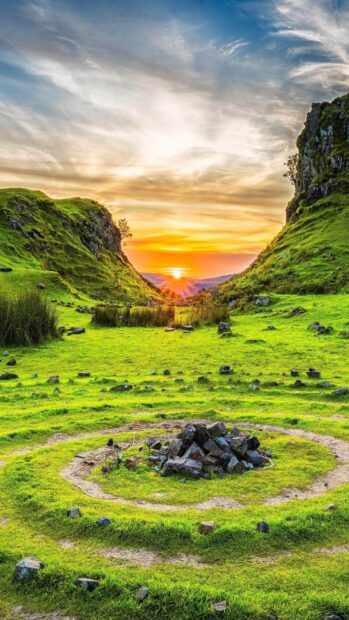 Green rocky landscape on Isle of Skye with circular stone pattern at sunset