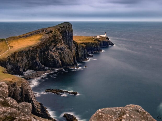 Rocky cliffs on Isle Of Skye with a lighthouse overlooking the sea