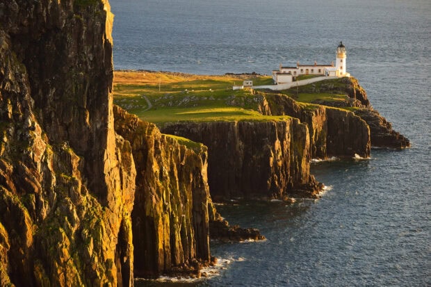Steep cliffs and a lighthouse on Isle of Skye overlooking the ocean at sunset