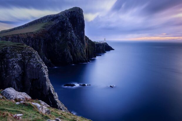 The Isle of Skye cliffside with a lighthouse overlooking the calm sea at sunset