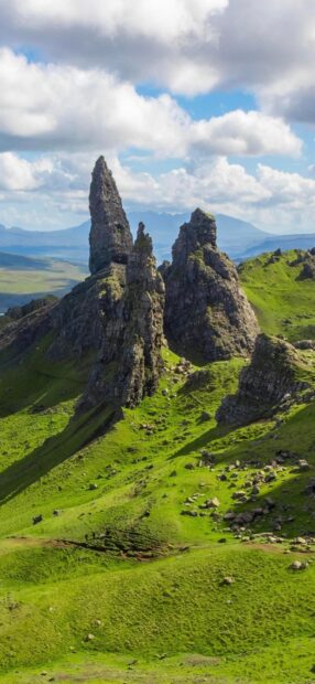 Majestic rock formations on Isle of Skye surrounded by green hills under blue sky