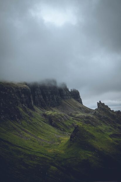 Mist covering the rugged cliffs of Isle of Skye with green hills below