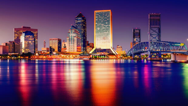 Night view of Jacksonville skyline with colorful lights reflecting on the river
