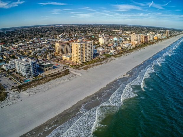 Aerial view of Jacksonville coastline with cityscape and ocean waves under a clear sky