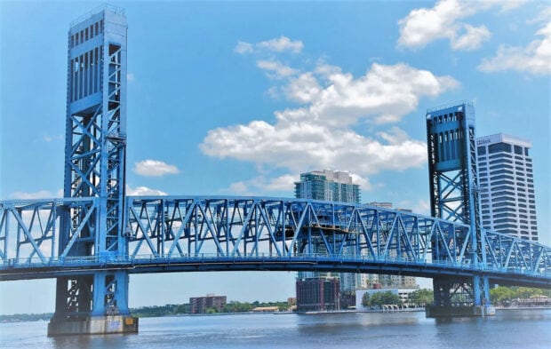 Blue steel bridge and city skyline in Jacksonville under a bright cloudy sky