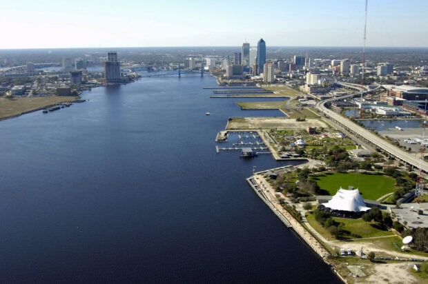 A panoramic cityscape of Jacksonville with riverfront parks and buildings under clear skies