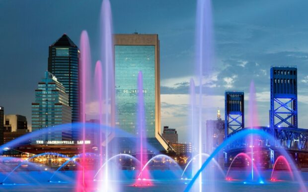 Colorful water fountains in Jacksonville cityscape at dusk with tall buildings in the background