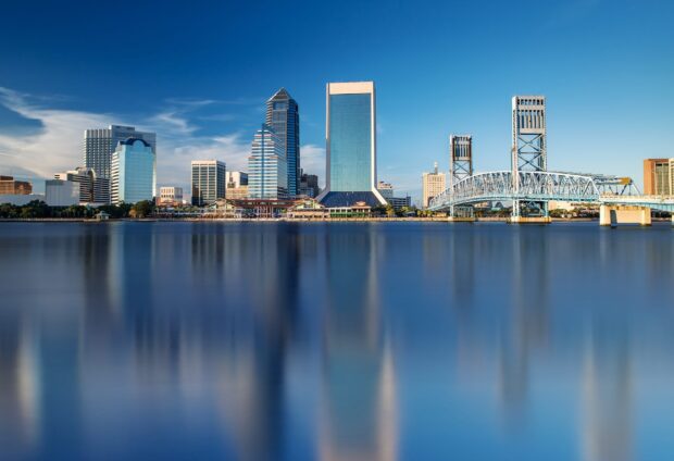 Downtown Jacksonville skyline reflecting over the river with clear blue sky and modern buildings