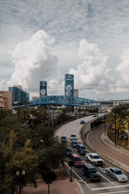 Blue bridge and busy road with cars in Jacksonville under cloudy sky