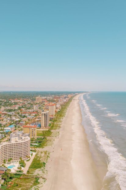 Aerial view of Jacksonville coastline showing sandy beach and cityscape under clear blue sky