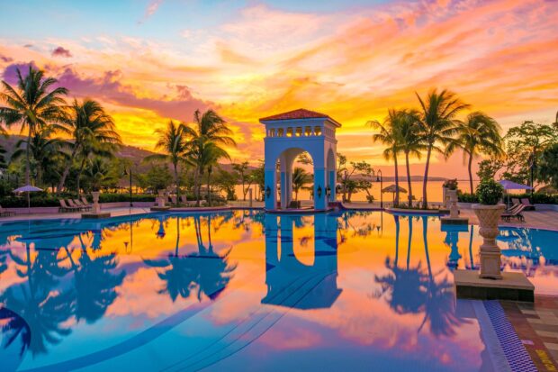 Tropical sunset in Jamaica with palm trees reflected in a calm swimming pool