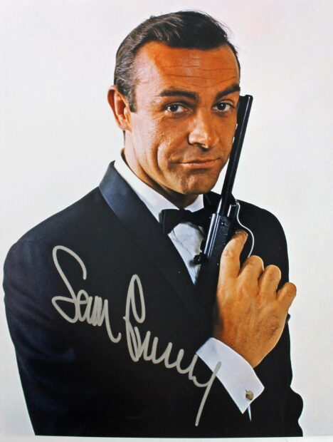 Sean Connery as James Bond holding a gun in a tuxedo with a confident expression