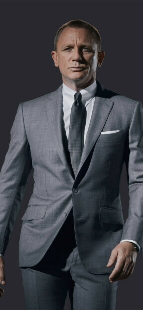 James Bond wearing a grey suit standing confidently against a dark background