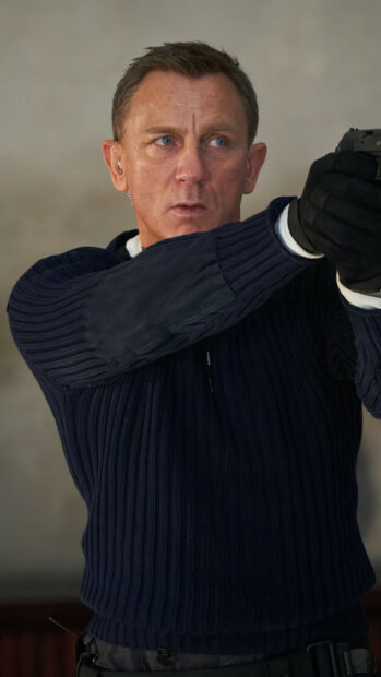 James Bond in a navy sweater aiming a gun with intense focus