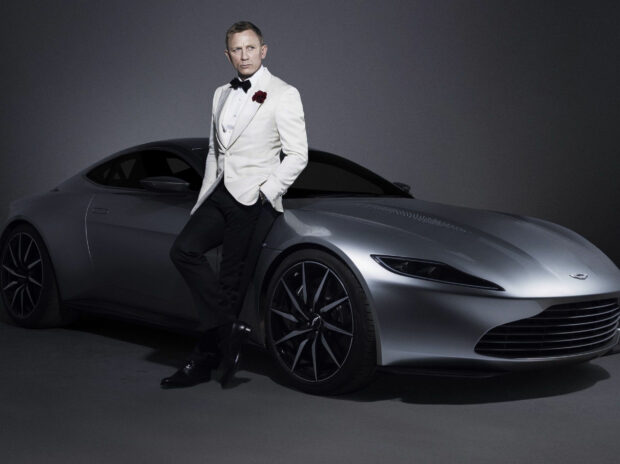 James Bond standing confidently next to a sleek silver sports car in a stylish suit