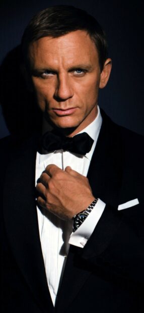 James Bond adjusting his bow tie wearing a suit and watch in a close up portrait