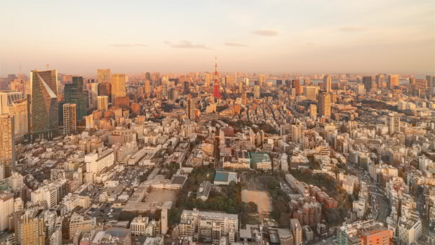 A panoramic view of Japan skyline featuring Tokyo Tower at sunset with city buildings and streets in warm light