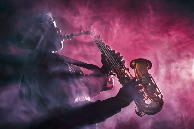 A jazz musician playing saxophone surrounded by purple smoke on stage
