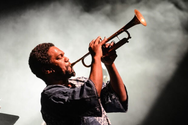 A jazz musician playing the trumpet passionately on stage with dramatic lighting and smoke background