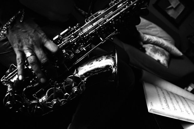 A close up of a jazz musician playing saxophone with sheet music nearby
