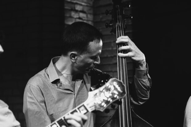 A man playing double bass passionately in a jazz band setting