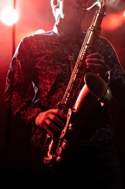 A musician playing saxophone on stage in a jazz performance with dramatic red lighting